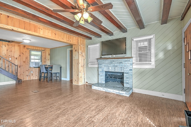 unfurnished living room with beam ceiling, wooden walls, wood-type flooring, and a fireplace