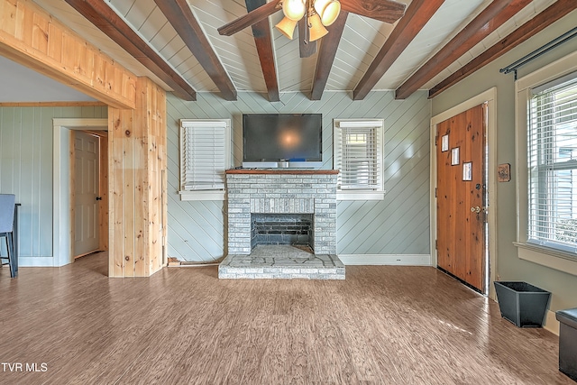 unfurnished living room featuring hardwood / wood-style flooring, wooden walls, and a wealth of natural light