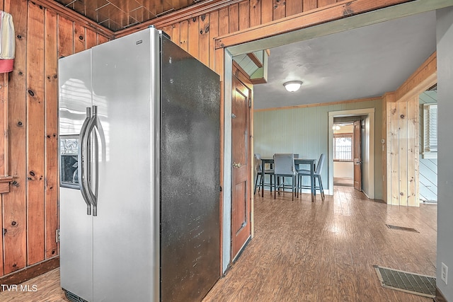 kitchen featuring dark hardwood / wood-style flooring, wooden walls, and stainless steel fridge with ice dispenser