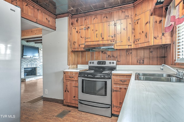 kitchen featuring range hood, sink, stainless steel range with electric cooktop, light wood-type flooring, and a fireplace