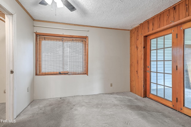 spare room featuring light carpet, wood walls, a textured ceiling, and ceiling fan