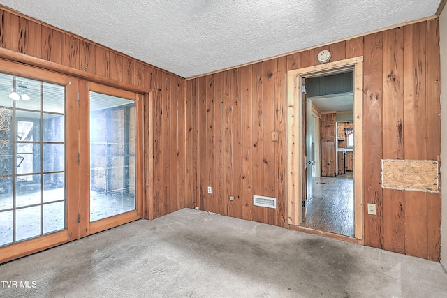 unfurnished room featuring wooden walls, carpet floors, and a textured ceiling