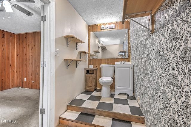 bathroom featuring vanity, toilet, and wood walls