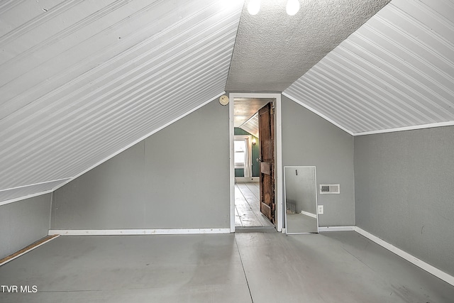 additional living space featuring a textured ceiling and vaulted ceiling