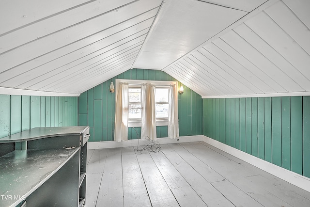 additional living space with vaulted ceiling, light hardwood / wood-style flooring, and wood walls