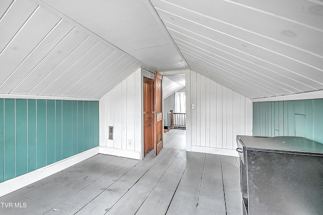 additional living space with lofted ceiling, wooden walls, and wood-type flooring