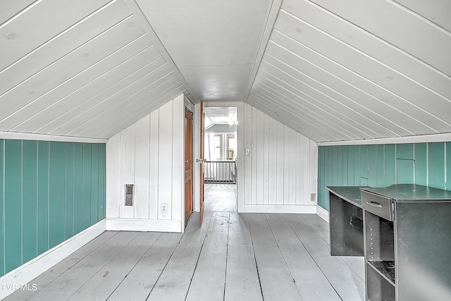 bonus room featuring vaulted ceiling, light hardwood / wood-style flooring, and wooden walls