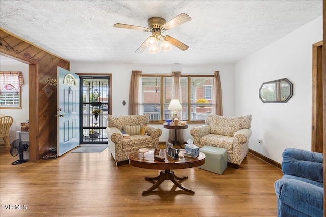 living room with a textured ceiling, hardwood / wood-style flooring, and ceiling fan