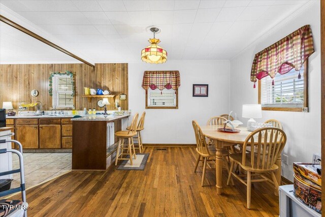 dining room with crown molding, wood walls, sink, and dark wood-type flooring