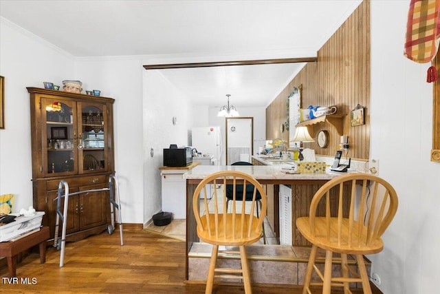 bar with ornamental molding, dark hardwood / wood-style floors, wood walls, a notable chandelier, and white fridge