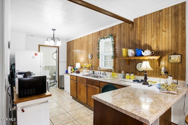 kitchen featuring hanging light fixtures, an inviting chandelier, wood walls, light tile patterned flooring, and white refrigerator