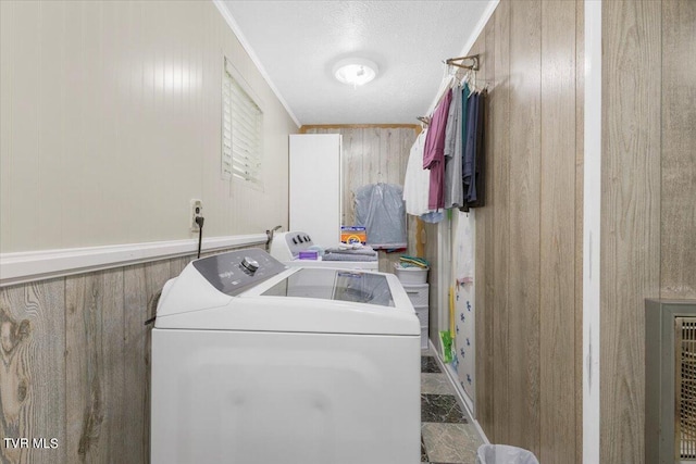 washroom with washer and dryer, wood walls, ornamental molding, and a textured ceiling