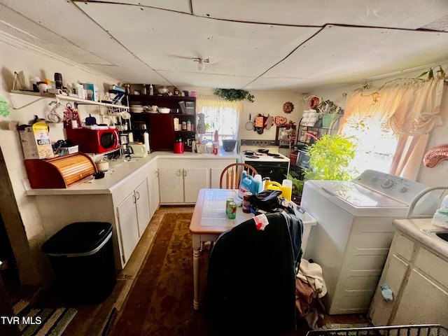 kitchen with washer / dryer, white range with electric stovetop, white cabinets, and a healthy amount of sunlight