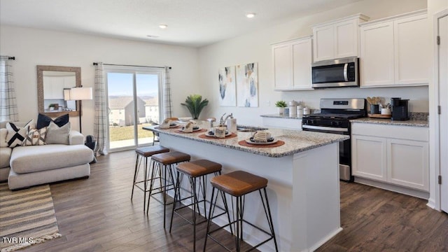 kitchen featuring dark wood-style floors, a kitchen bar, appliances with stainless steel finishes, and white cabinets