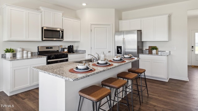 kitchen with appliances with stainless steel finishes, white cabinetry, a sink, and dark wood-style floors