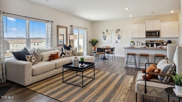 living room with dark wood-style floors, baseboards, and recessed lighting