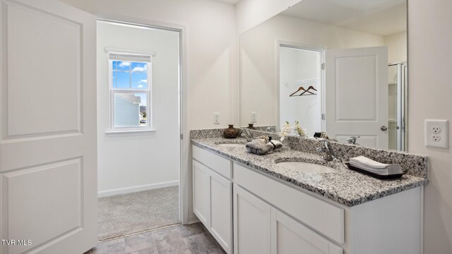 full bathroom with a sink, baseboards, and double vanity