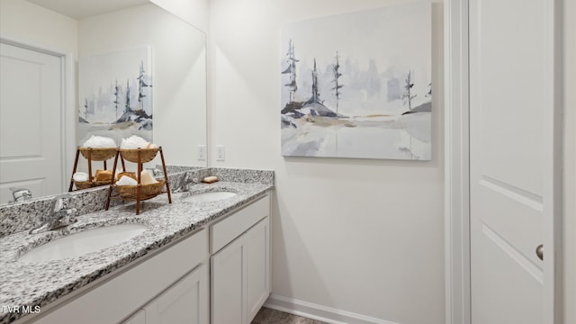 full bath featuring double vanity, baseboards, and a sink