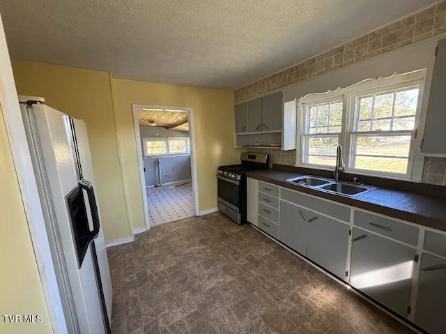 kitchen with white fridge with ice dispenser, sink, a textured ceiling, white cabinetry, and gas range