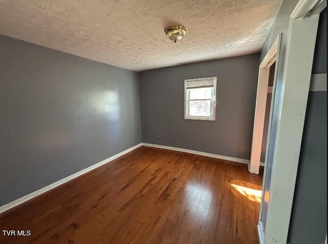 spare room with a textured ceiling and hardwood / wood-style flooring