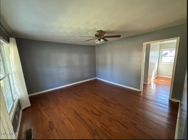 empty room with dark hardwood / wood-style floors and ceiling fan