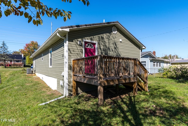 rear view of property featuring a yard, central AC, and a wooden deck