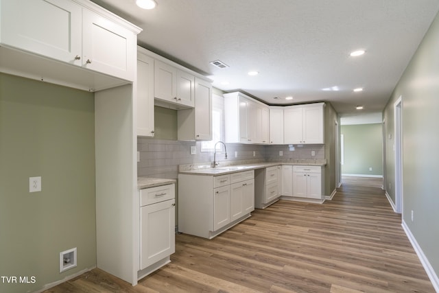 1608 E Fairview Ave, Johnson City, TN 37601 - kitchen featuring a sink, decorative backsplash, light wood finished floors, baseboards, and white cabinetry