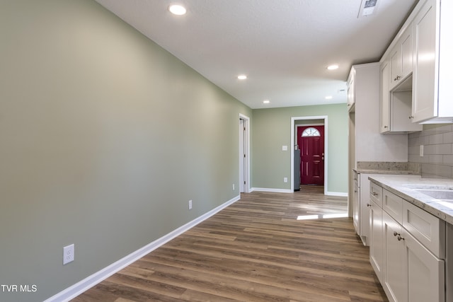 kitchen with white cabinetry, light stone countertops, and dark wood-type flooring