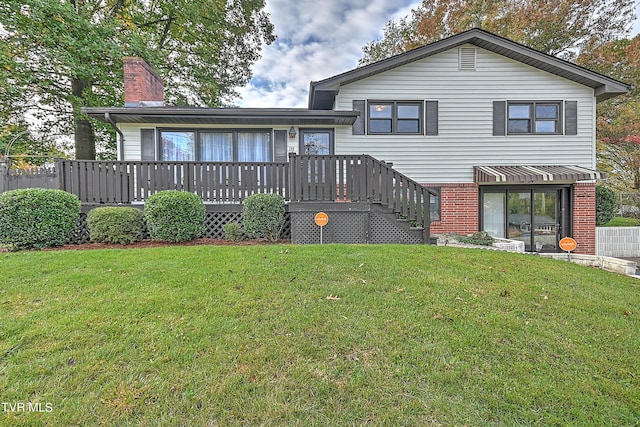 rear view of property featuring a lawn, a chimney, brick siding, and a wooden deck