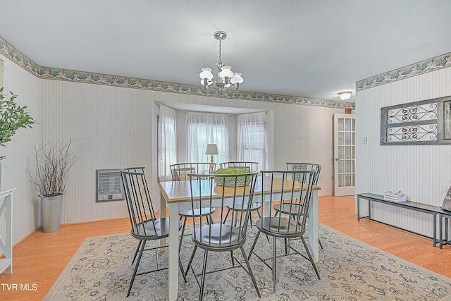 dining space featuring baseboards, a chandelier, wood finished floors, and wallpapered walls