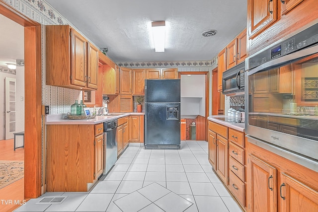 kitchen featuring black appliances, brown cabinets, light tile patterned flooring, light countertops, and visible vents