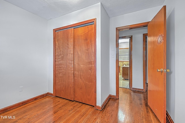 unfurnished bedroom with baseboards, wood finished floors, and a closet