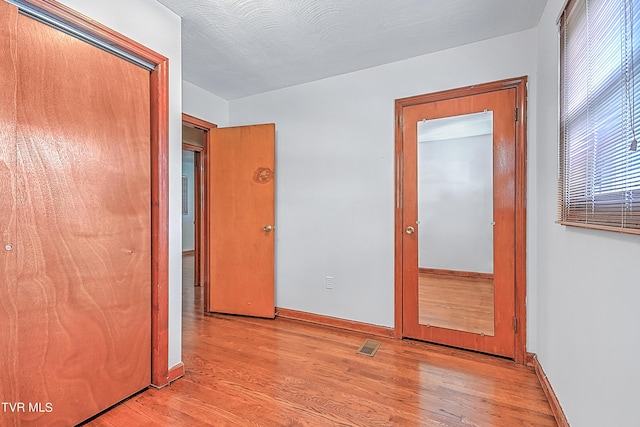 unfurnished bedroom with light wood finished floors, baseboards, a closet, and visible vents
