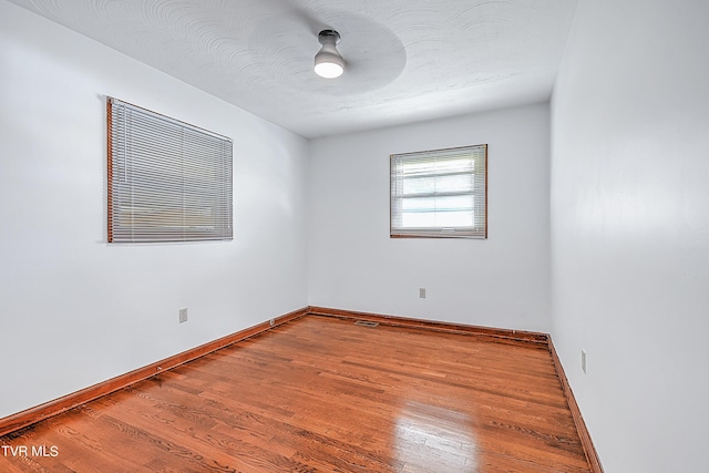 spare room with baseboards and wood finished floors