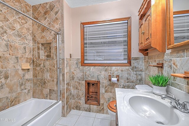 full bathroom with vanity, toilet, tile walls, tile patterned flooring, and washtub / shower combination