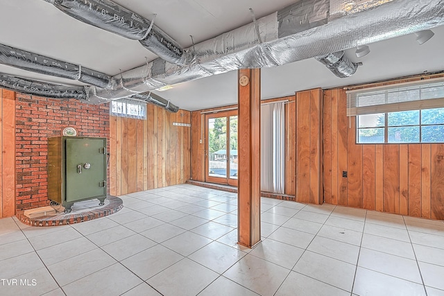basement with wooden walls, a wealth of natural light, and light tile patterned floors
