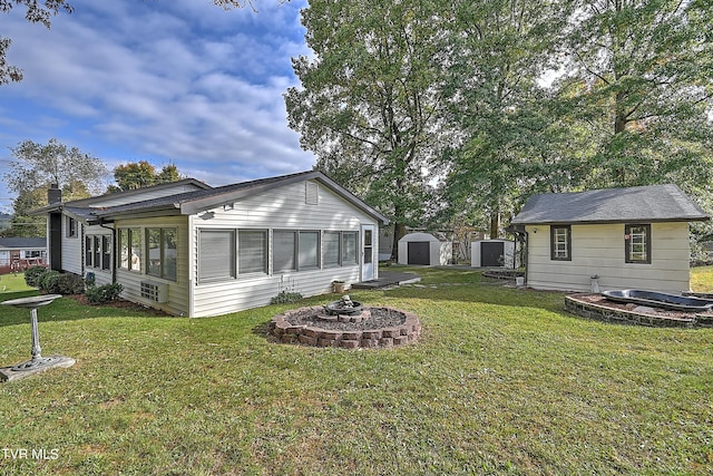 back of house featuring an outdoor structure, a yard, a shed, and an outdoor fire pit