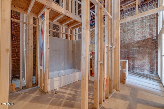 bathroom featuring brick wall and a bathing tub