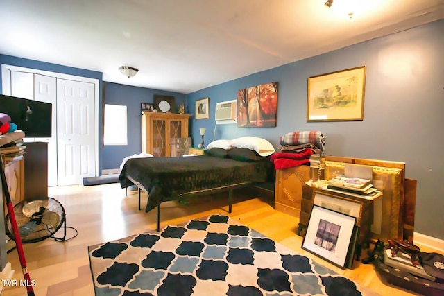 bedroom with a closet, a wall mounted air conditioner, and light wood-type flooring