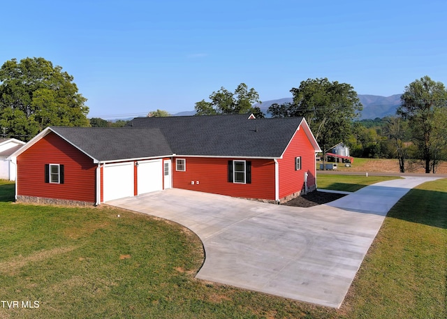 ranch-style home with a mountain view, a front yard, and a garage