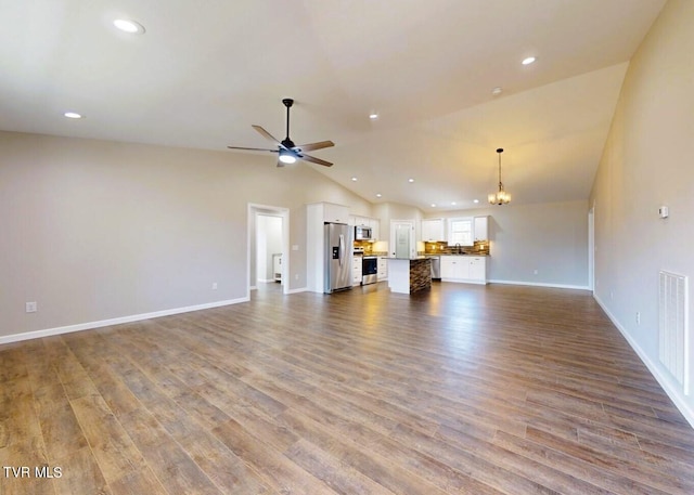 unfurnished living room featuring light hardwood / wood-style floors, vaulted ceiling, and ceiling fan with notable chandelier