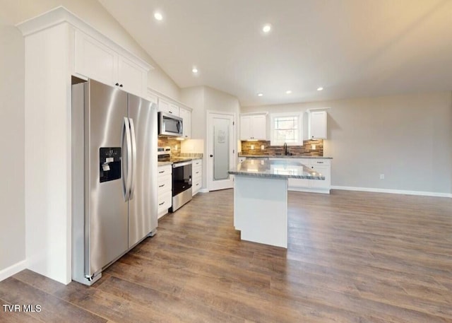 kitchen featuring lofted ceiling, dark hardwood / wood-style flooring, appliances with stainless steel finishes, a kitchen island, and white cabinetry