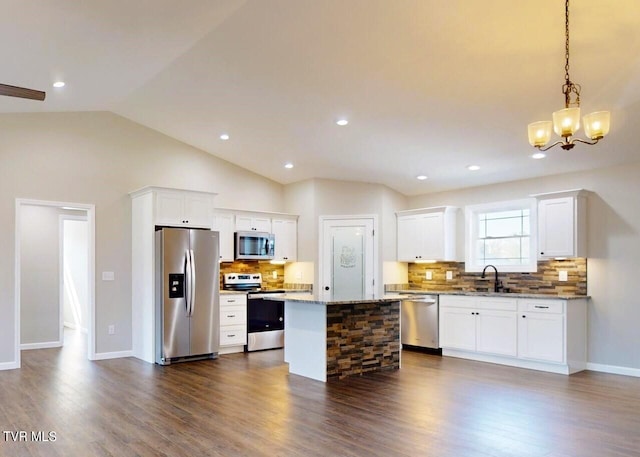 kitchen with a kitchen island, light stone countertops, dark hardwood / wood-style floors, pendant lighting, and stainless steel appliances