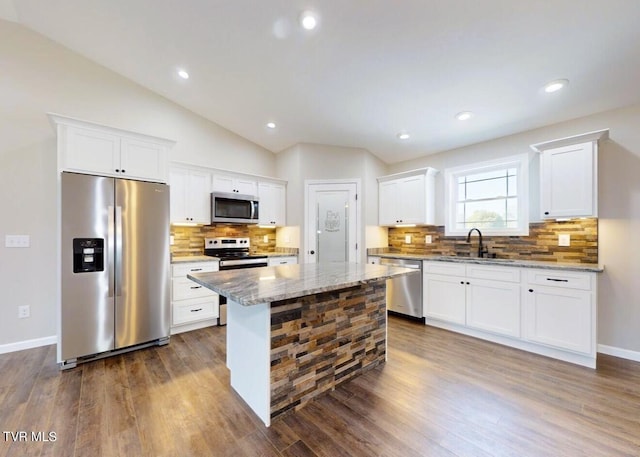 kitchen featuring stainless steel appliances, vaulted ceiling, dark hardwood / wood-style floors, and a kitchen island