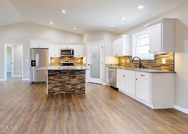 kitchen with dark wood-type flooring, a center island, white cabinetry, appliances with stainless steel finishes, and light stone counters