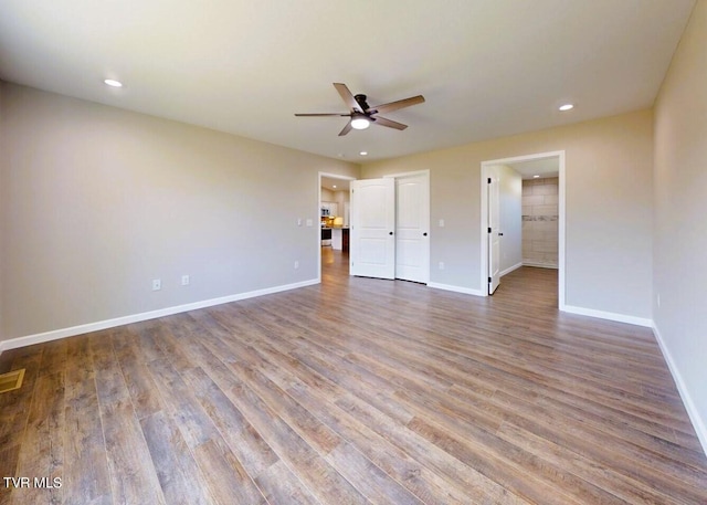 interior space with hardwood / wood-style flooring, connected bathroom, and ceiling fan