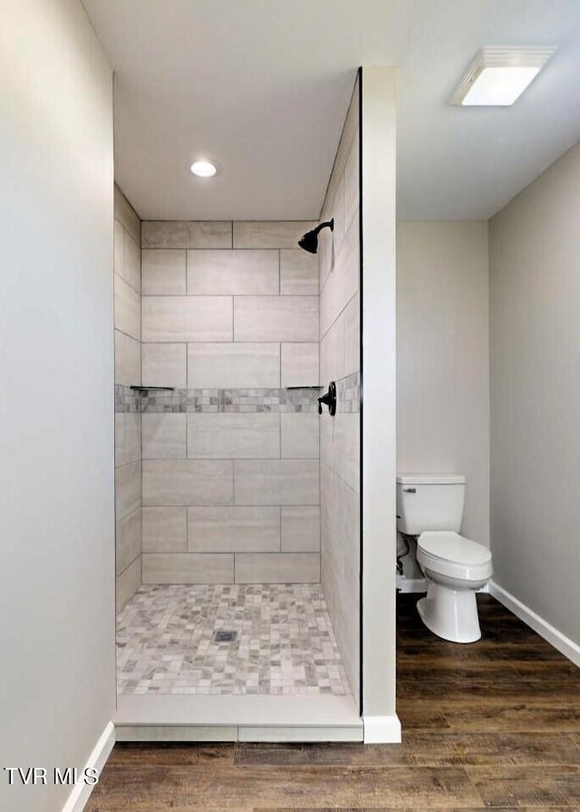 bathroom featuring tiled shower, wood-type flooring, and toilet