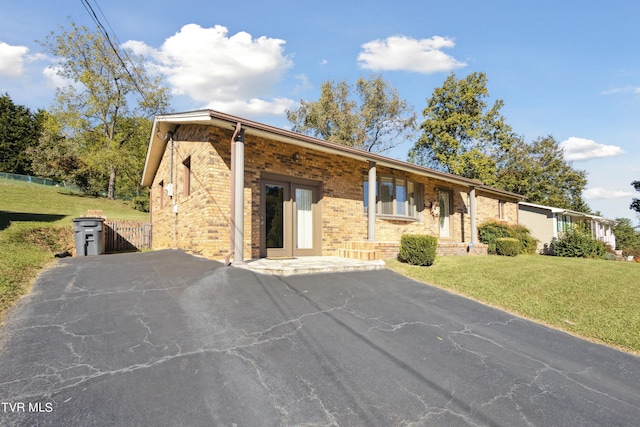 view of front facade with brick siding, aphalt driveway, and a front lawn