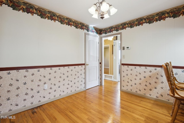 unfurnished room with hardwood / wood-style floors and an inviting chandelier