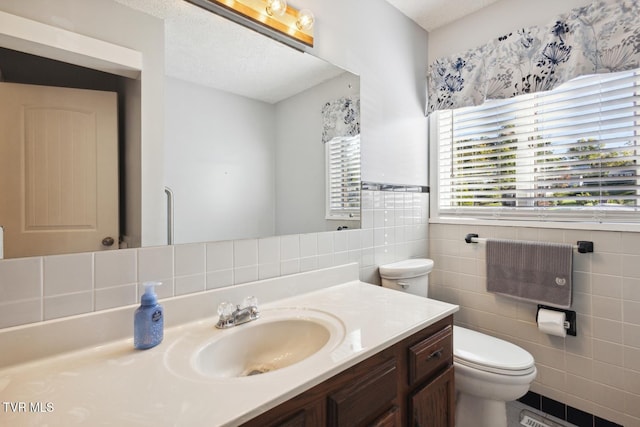 bathroom with vanity, toilet, tile walls, and a textured ceiling